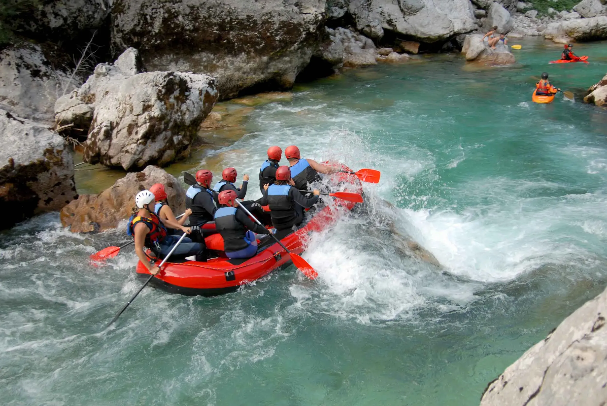 "Group of people navigating a rocky river, surrounded by rugged terrain."