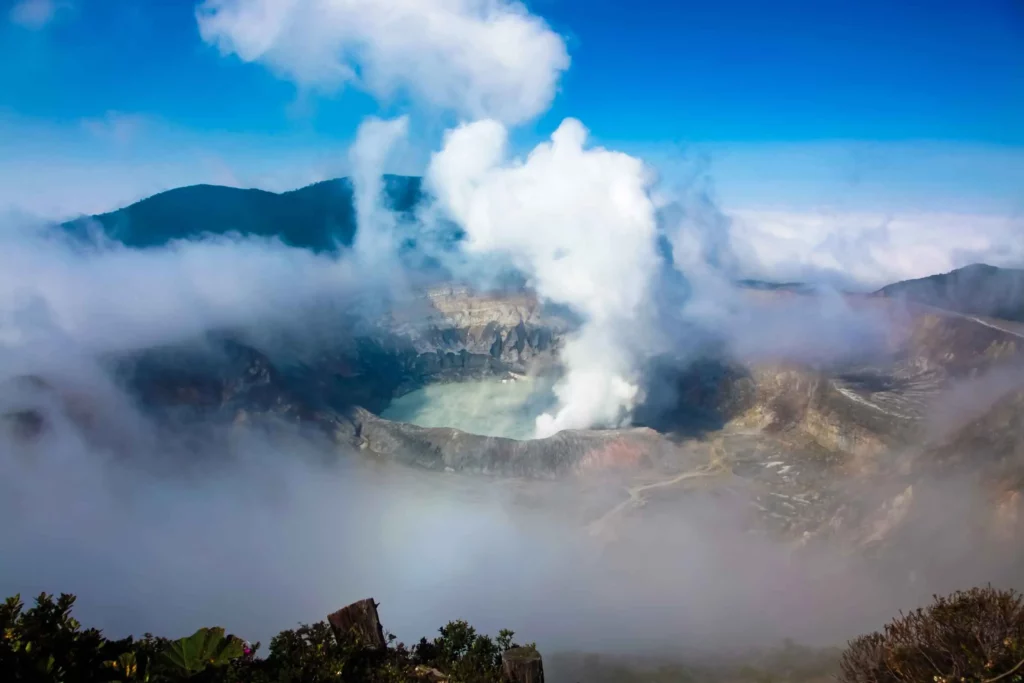 "Majestic volcano emitting smoke from its crater, set against a dramatic sky."