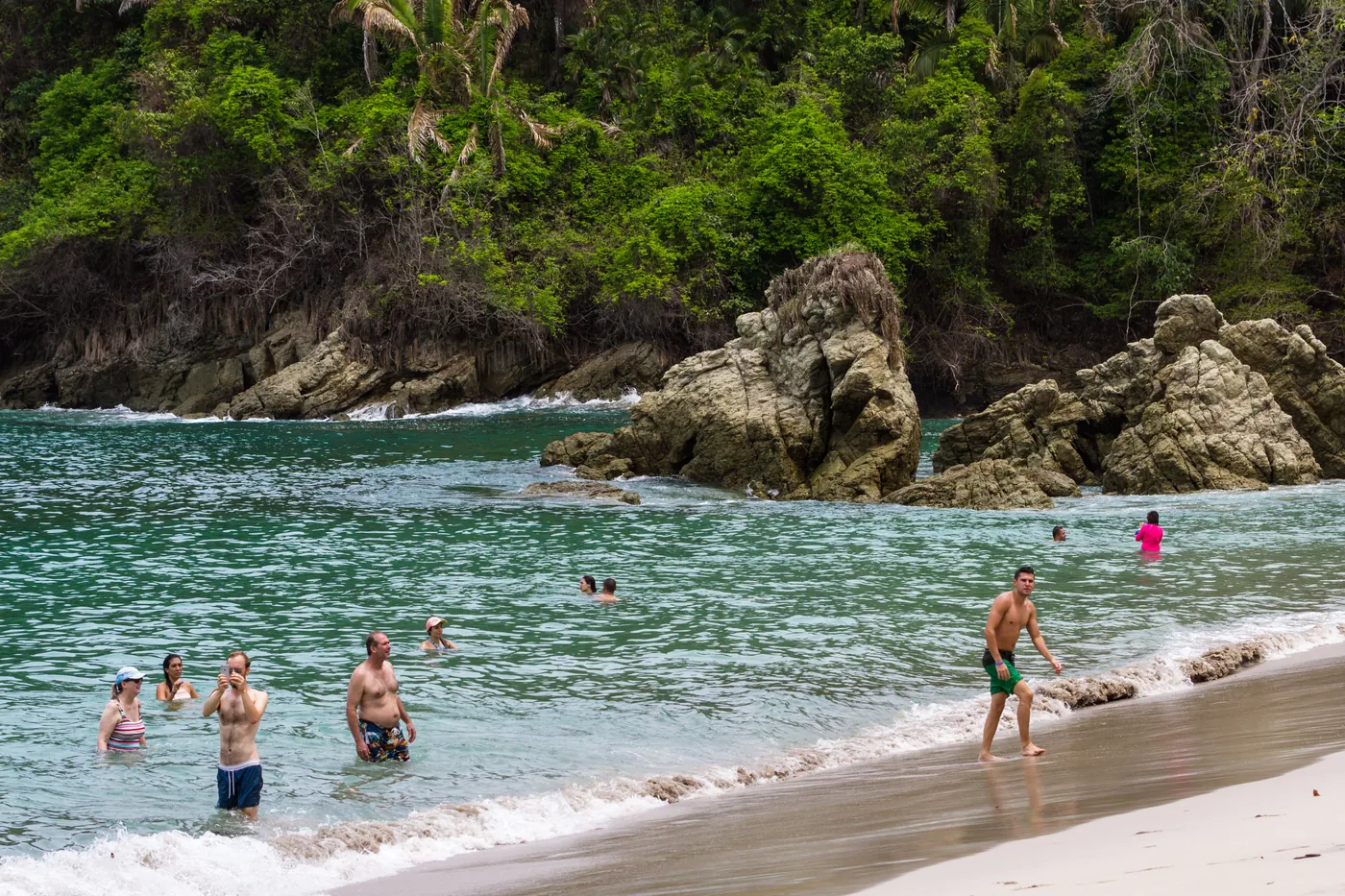 Travellers swimming at a beach cove in Manuel Antonio, Costa Rica