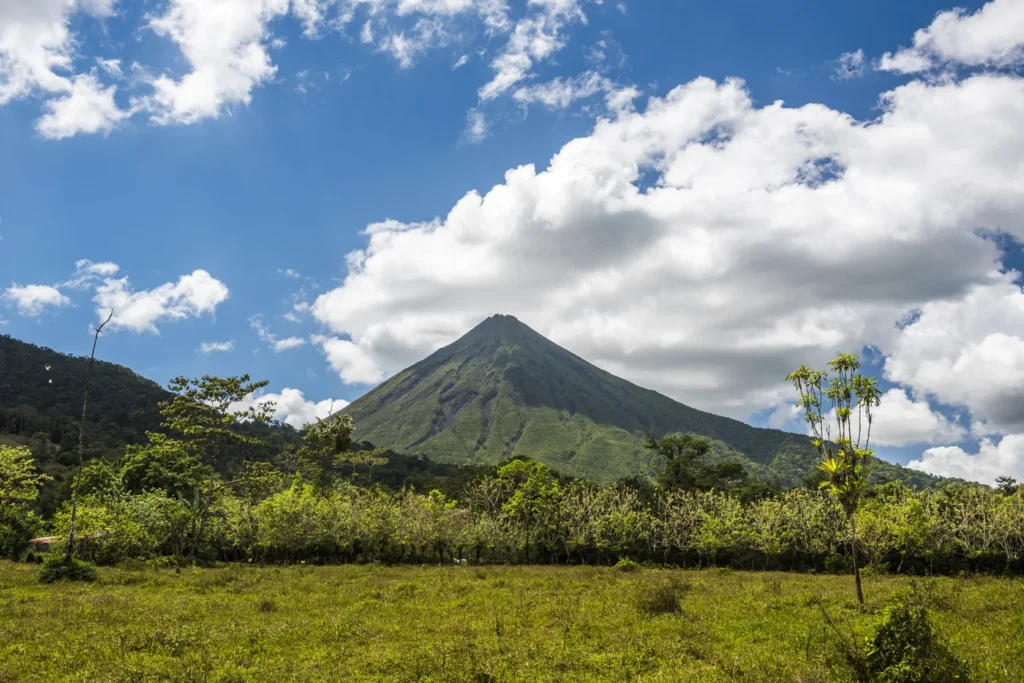 Der Vulkan Arenal ragt über grünem Ackerland und Wald in Costa Rica auf