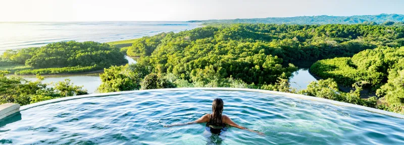 Ospite che nuota in una piscina a sfioro affacciata sulla foresta pluviale