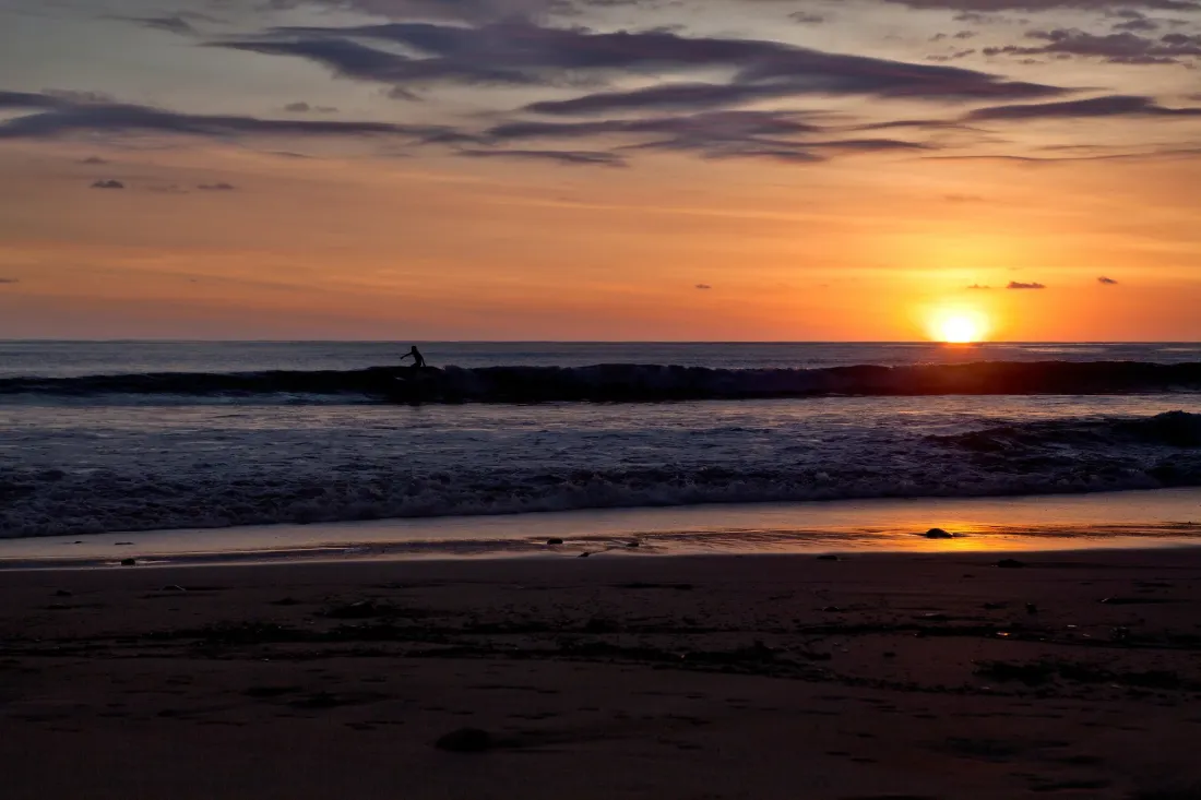 Surfers at Santa Teresa beach at sunset